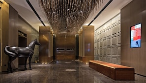 A modern hotel lobby with a horse sculpture, a bench, and a digital display on the wall. - Paco Hotel Chebeinan Metro Guanghzou (Guangzhou)