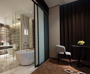 A modern bathroom with a bathtub, glass shower enclosure, and a chair near a table with flowers. - Paco Hotel Chebeinan Metro Guanghzou (Guangzhou)