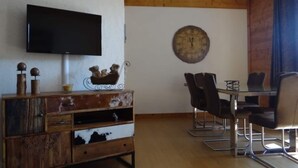 Ein Essbereich mit einem Holztisch, Metallstühlen und einer Wanduhr.