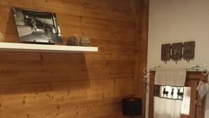 Ein Schlafzimmer einer Holzhütte mit Bett, Nachttisch, Lampe und einem Regal mit einem Foto.