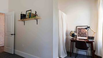 A room with a desk, a globe, a framed picture, and a shelf with books and decorative items.