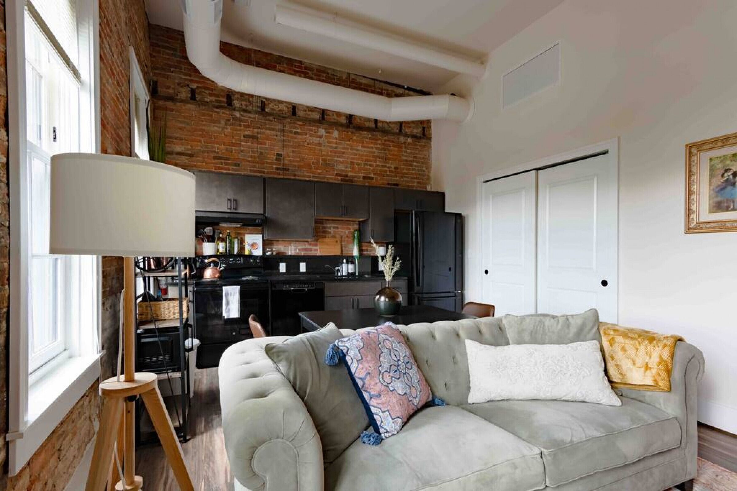 A living room with a sofa, a lamp, and a kitchen in the background.