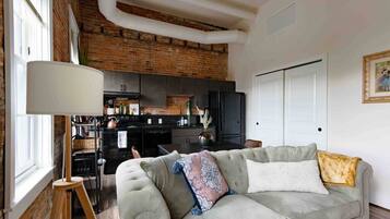 A living room with a sofa, a lamp, and a kitchen in the background.