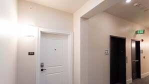 A hallway with a white door labeled 212, an elevator, and an exit sign. - Thompson 212 · Thompson Block Loft - Modern and Historic (Ypsilanti)