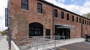 A brick building with a sign reading "Thompson Lofts." - Thompson 212 · Thompson Block Loft - Modern and Historic (Ypsilanti)