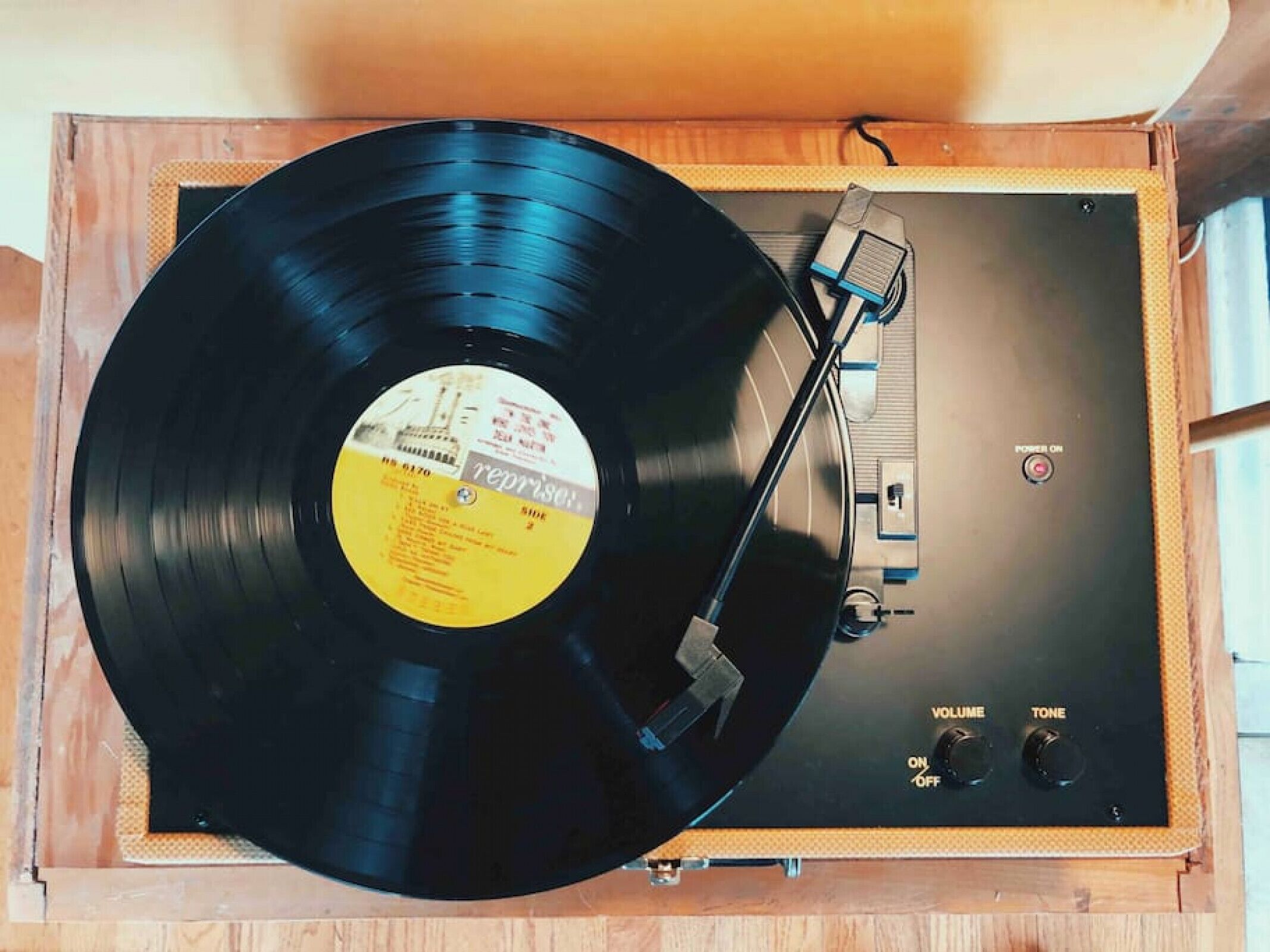 A turntable with a vinyl record, volume and tone controls, and a power switch.