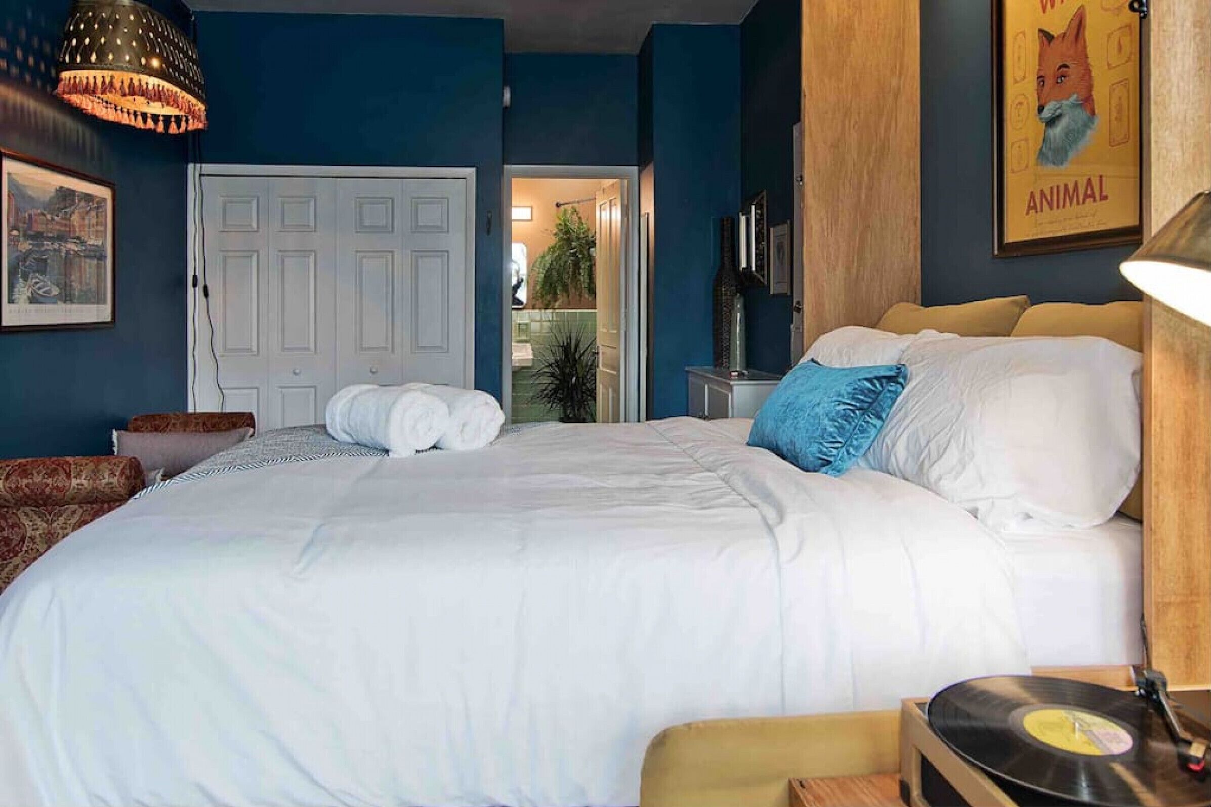 A bedroom with a bed, a record player, a door, and a poster on the wall.