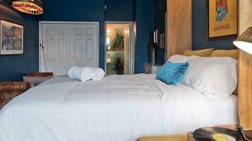 A bedroom with a bed, a record player, a door, and a poster on the wall.
