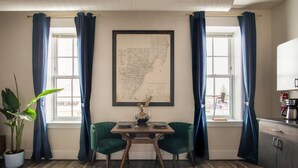 Un rincón comedor con una mesa lista para dos, un mapa enmarcado en la pared y una planta en maceta.