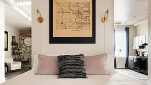 Un dormitorio con una cama grande, un mapa en la pared y una cocina al fondo.