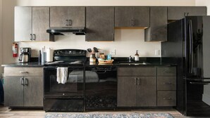 Una cocina moderna con armarios oscuros, una estufa negra y un refrigerador.