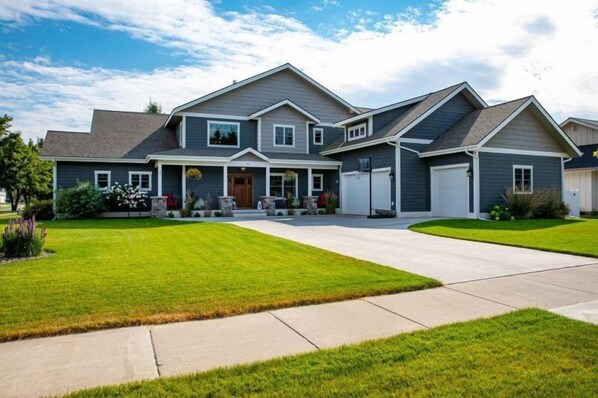 A two-story house with a front porch, a garage, and a well-maintained lawn.