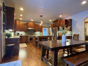 A modern kitchen with wooden cabinets, a central island, and a dining table.