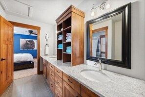 A modern bathroom with a large mirror, wooden cabinetry, and a built-in shower area.
