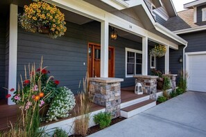 A house with a porch, stone steps, and flower planters.
