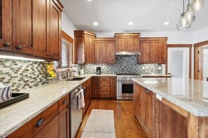 A kitchen with wooden cabinets, a tiled backsplash, a stainless steel range hood, and a granite countertop.