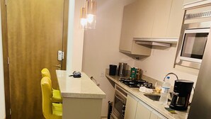 A compact kitchen with a central island, a microwave, a stove, and a refrigerator. - LOCAR-IN GRAMADO- Conte (Gramado)