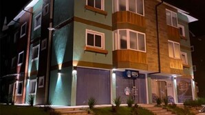 A multi-story building with a mix of exterior finishes, including wood and stone, and a visible entrance with steps leading up to the door. - LOCAR-IN GRAMADO- Conte (Gramado)