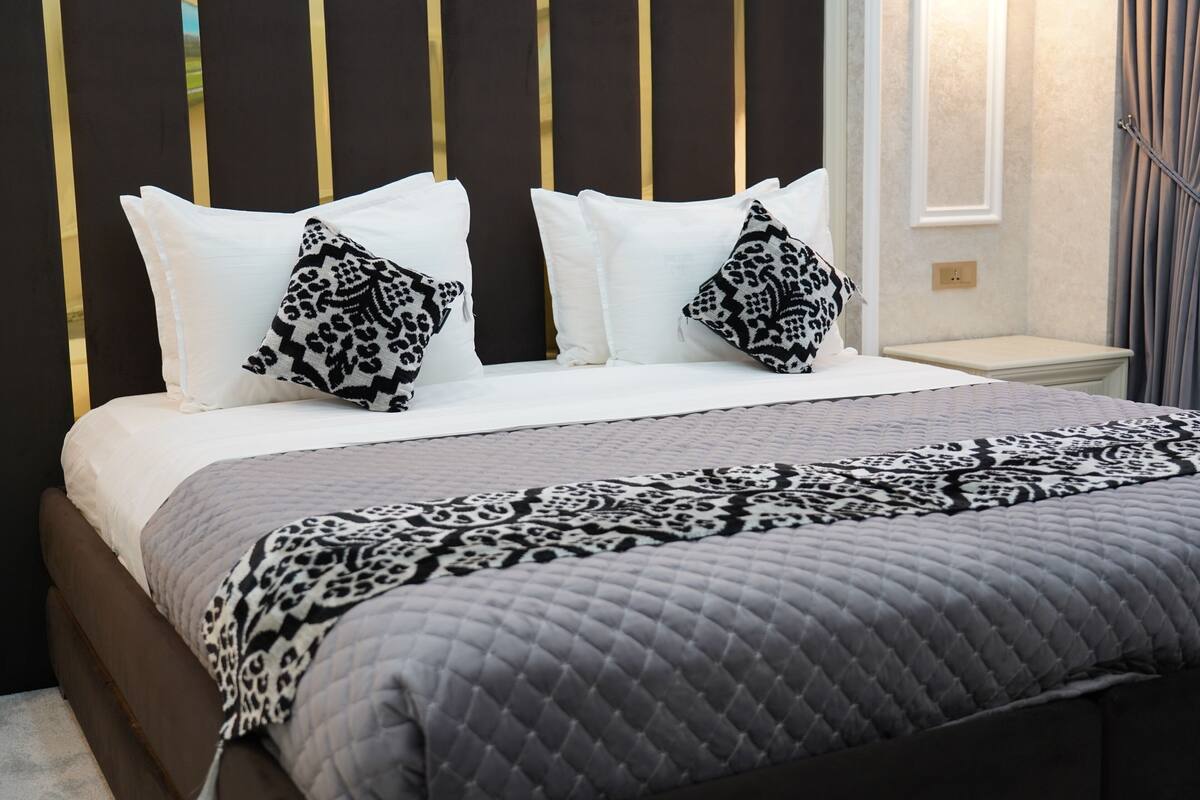 A neatly made bed with a patterned quilt and two leopard print pillows.