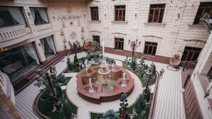 A courtyard with a central fountain, surrounded by greenery and seating areas. - Shaxzoda Elite Hotel (Samarkand)
