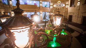 A lobby with ornate metal chandeliers, a fountain, and a high-ceilinged room with large windows. - Shaxzoda Elite Hotel (Samarkand)