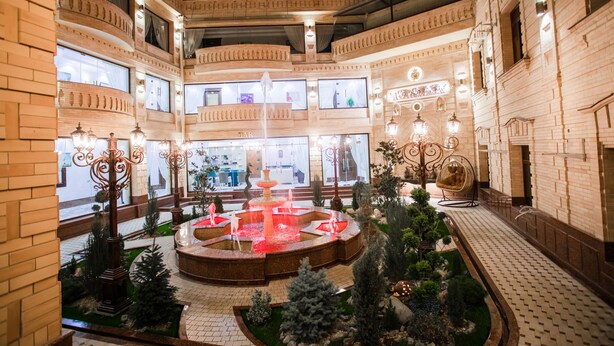 A multi-level atrium with a central fountain, surrounded by brick walls and decorative lighting. - Shaxzoda Elite Hotel (Samarkand)