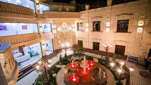 A multi-level hotel atrium with a central fountain, multiple balconies, and a well-lit interior. - Shaxzoda Elite Hotel (Samarkand)