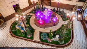 A luxurious hotel lobby with a central fountain, a grand staircase, and a well-maintained garden area. - Shaxzoda Elite Hotel (Samarkand)