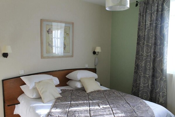A neatly made bed with a patterned bedspread, two wall-mounted lamps, and a framed picture on the wall. - Logis Moulin De Saint Verand (Saint-Verand)