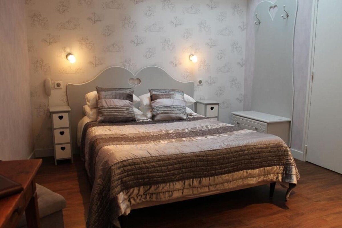 A bedroom with a bed, bedside tables, a nightstand, a dresser, and a wardrobe.