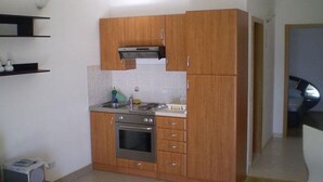 A compact kitchen with wooden cabinets, a built-in oven, and a microwave. - Apartment in Duće with Seaview, Balcony, Air condition, WIFI (5060-1) (Duce)
