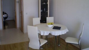 A dining area with a round table, white chairs, and a bowl of fruit. - Apartment in Duće with Seaview, Balcony, Air condition, WIFI (5060-1) (Duce)