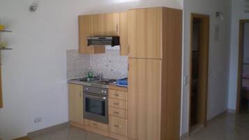 Een koelkast, een oven, een waterkoker, kookgerei, borden en bestek
