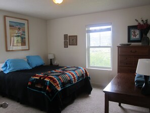 Une chambre à coucher avec un lit, une table de chevet, une commode, une fenêtre et un tableau au mur.