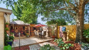 Un jardin avec une terrasse, du mobilier d’extérieur, des plantes en pot et une clôture en bois.