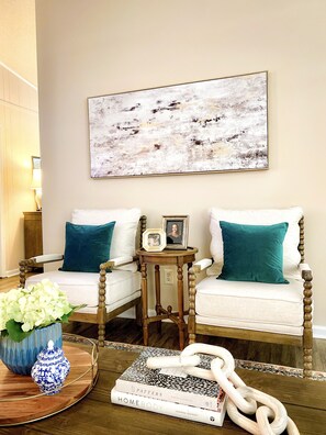 A living room with a sofa, a coffee table, and a painting on the wall.