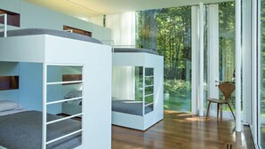 A modern room with bunk beds, a large window with a forest view, and a wooden floor. - Modern Glass House designed by renowned architect Thomas Phifer (Hudson)