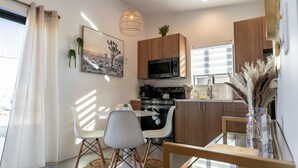 A modern kitchen with a dining area, featuring a microwave, stove, and white cabinets. - 15%DISCOUNT❤Hammocks❤Close 2 Downtown❤Fully Fenced (Joshua Tree)