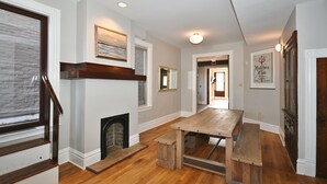 A spacious living room with hardwood flooring, a fireplace, a wooden bench, and a dining table. - Breathtaking Spacious PGH Skyline Loft On Carson Street (Pittsburgh)
