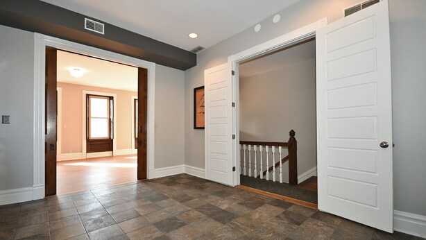 A hallway with a wooden floor, white doors, and a staircase with a white railing. - Breathtaking Spacious PGH Skyline Loft On Carson Street (Pittsburgh)
