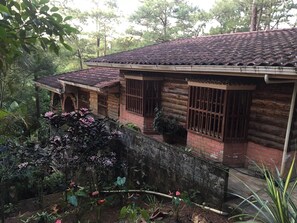 Surrounded by lush greenery, this cabin offers a secluded retreat with a cozy porch and a chimney.