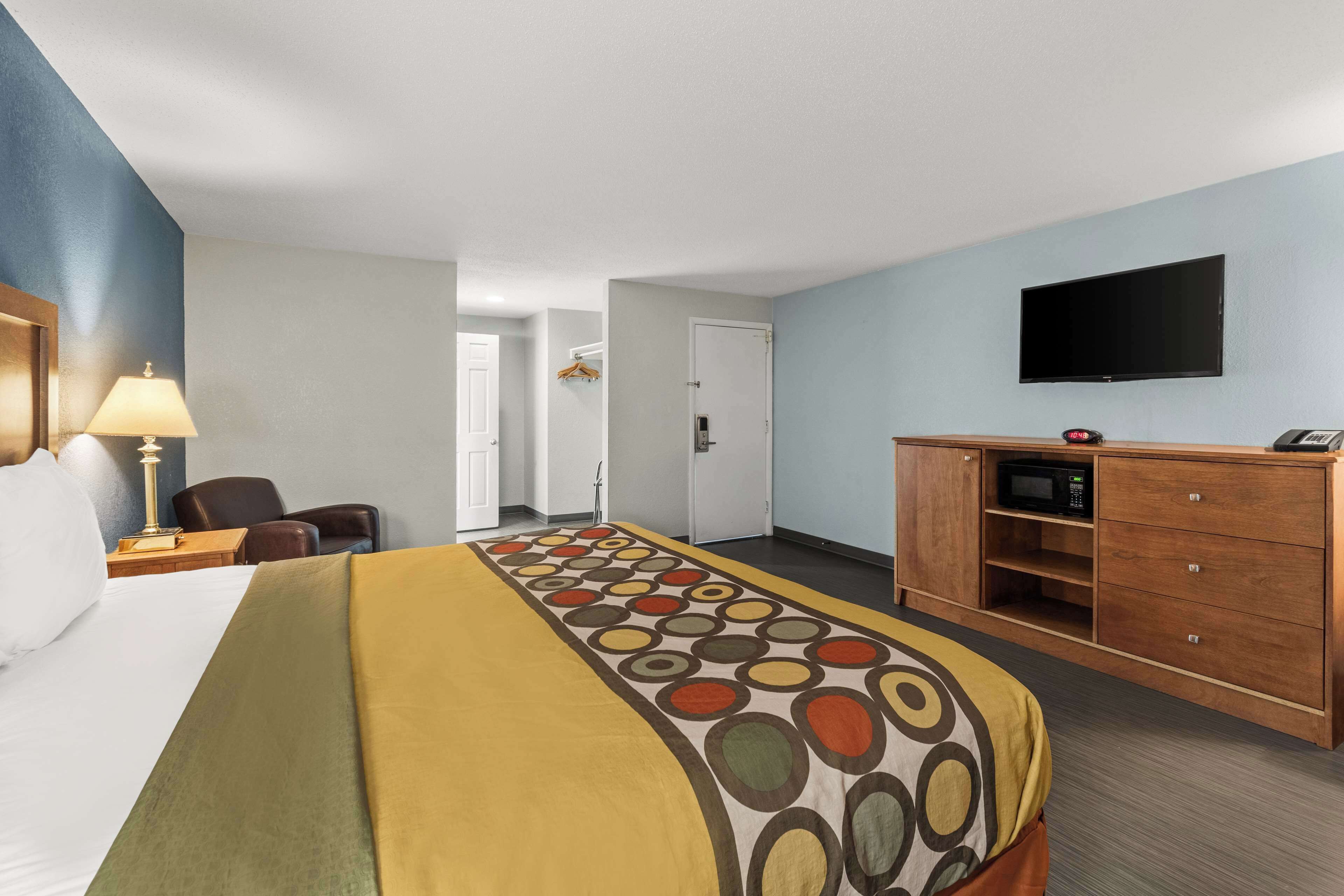 Une chambre d’hôtel comprenant un lit, un bureau avec une lampe, une télévision et une armoire.
