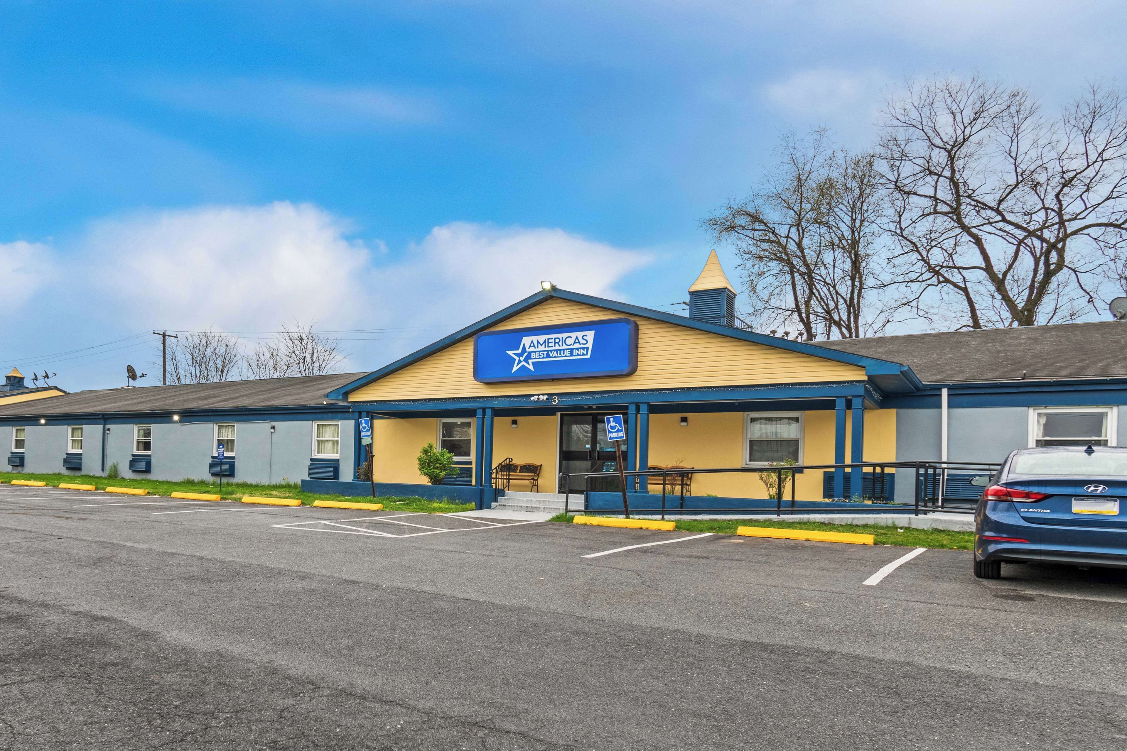 A motel with a blue and yellow exterior, a signboard, and a parking lot.