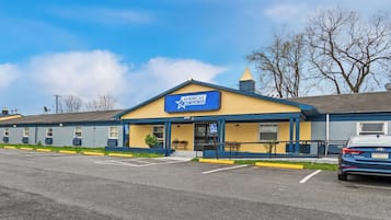 A motel with a blue and yellow exterior, a signboard, and a parking lot.