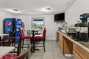 A compact kitchen with a refrigerator, a coffee machine, and a television above the counter. - Americas Best Value Inn Carlisle (Carlisle)
