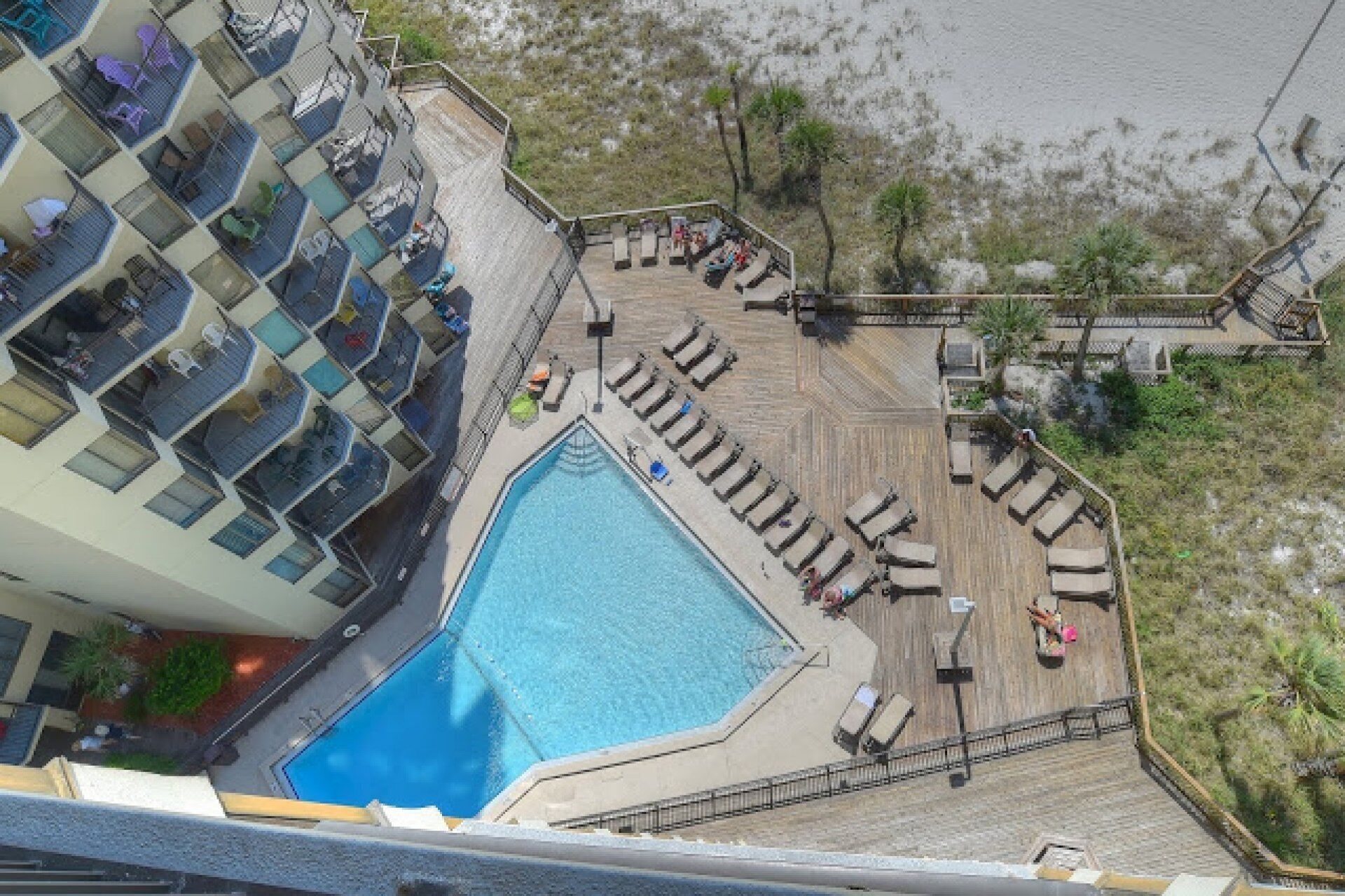 A pool area with lounge chairs and a swimming pool, surrounded by a building with balconies.