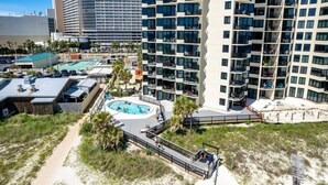 A high-rise hotel with multiple balconies, a swimming pool, and a beach area. - Sunbird 1103 West (Panama City Beach)