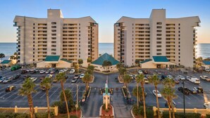 A hotel with a symmetrical facade, multiple floors, and a central courtyard with palm trees. - Sunbird 1103 West (Panama City Beach)