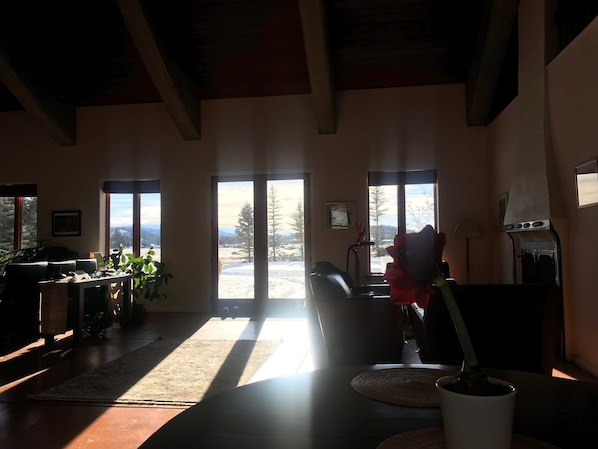 A spacious living room with large windows, a fireplace, and a view of a snowy landscape.