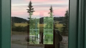 En vy genom ett fönster, där en person som står i en hall speglas.